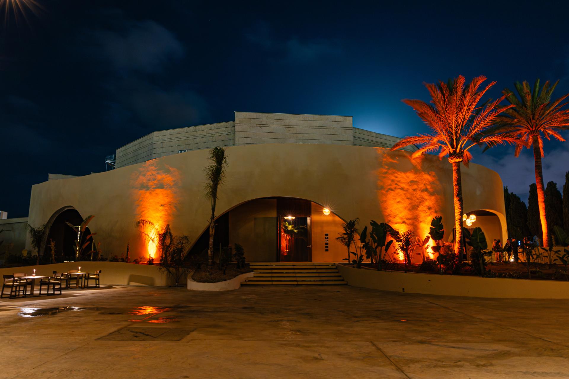 Amok - Mediterranean venue exterior with palm trees and warm lighting at night